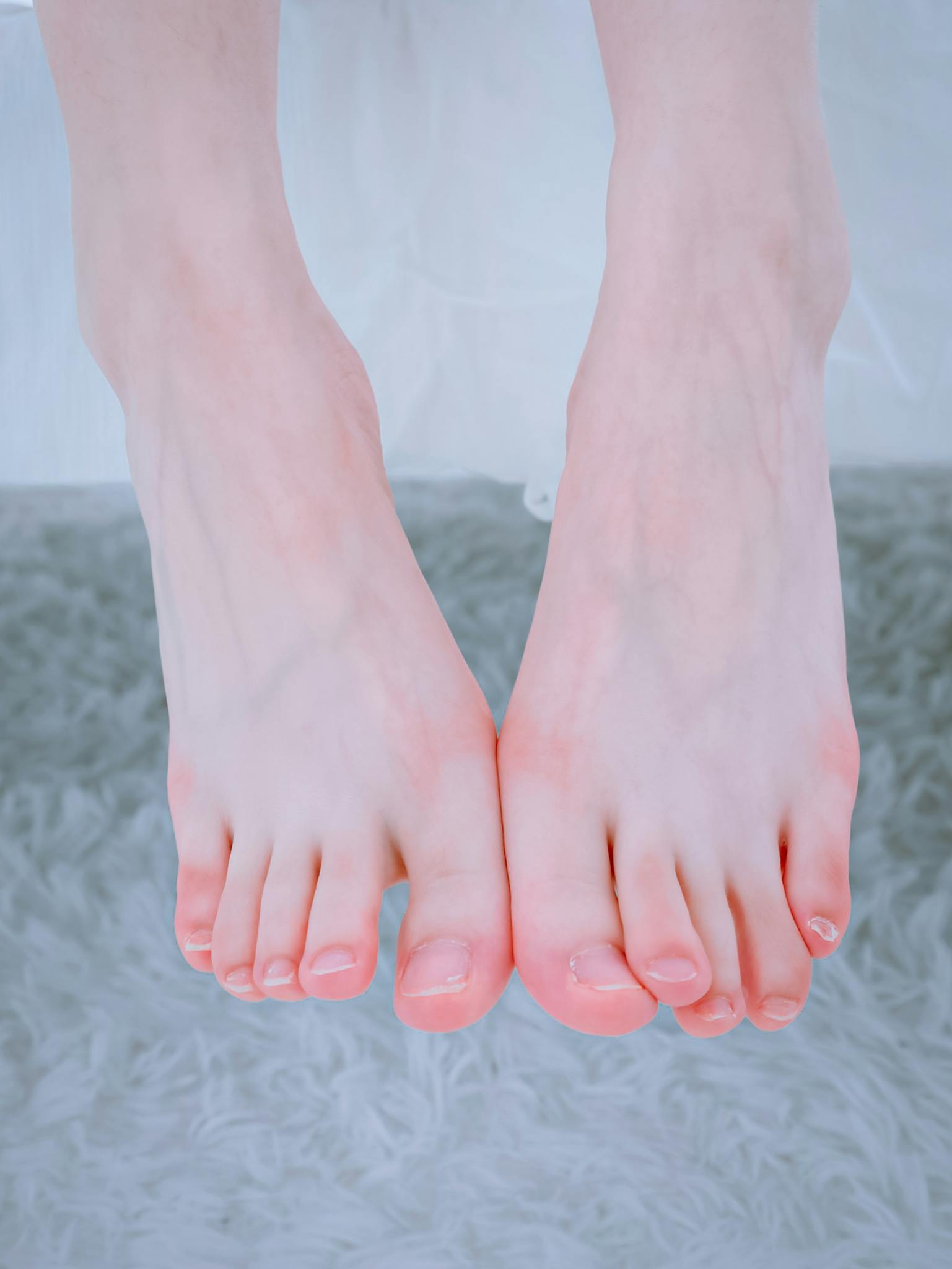 Close-up image of bare feet resting on a soft, textured surface, emphasizing skin tone and texture.